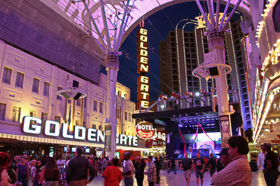 People on illuminated street in city at night