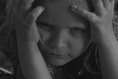 Close-up portrait of cute girl with head in hands