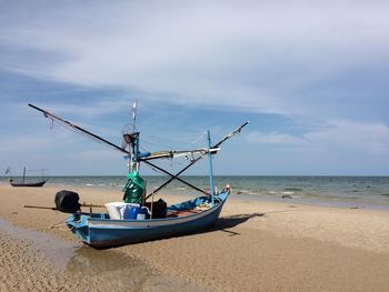 Fishing boat on beach against sky