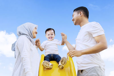 Low angle view of father and son against sky