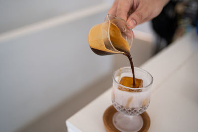 Cropped hand holding drink on table