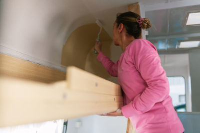 Woman painting ceiling at home