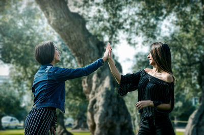 Rear view of friends standing against trees