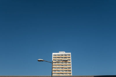 Low angle view of street light and residential building against clear blue sky