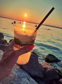 Person holding ice cream at beach during sunset