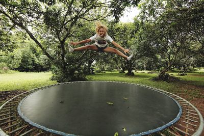 Portrait of woman jumping against trees