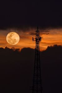 Low angle view of communications tower against sky at night