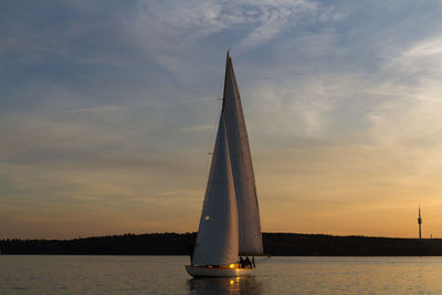 Sailboat in sea against cloudy sky