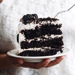 Midsection of woman holding fresh cake slice