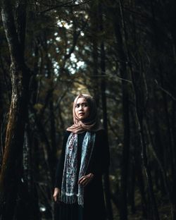 Woman standing by tree in forest