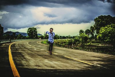 Man standing by road against sky
