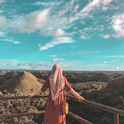 Rear view of woman standing on mountain against sky