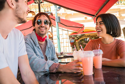 Smiling friends having discussion sitting at cafe