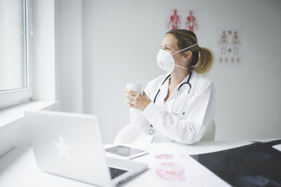 Smiling doctor holding coffee cup at clinic