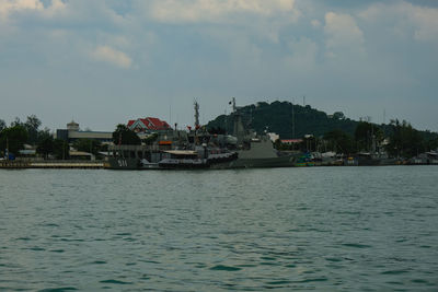 Boats in sea by buildings against sky