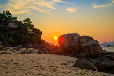 Rocks on beach against sky during sunset