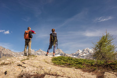 Rear view of men standing on rock against sky