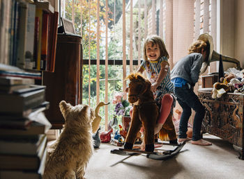 Happy siblings playing at home with dog sitting in foreground