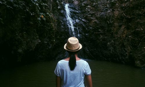 Rear view of woman standing against waterfall