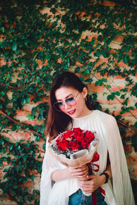 Beautiful young woman standing by flowering plants