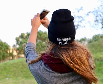 Rear view of woman photographing on field