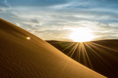 Scenic view of sandy desert against sky on sunny day
