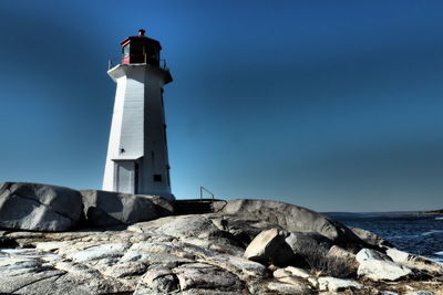 Lighthouse by sea against sky