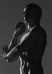 Side view of shirtless man against gray background