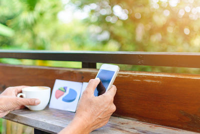 Cropped image of woman with mobile phone and coffee at table