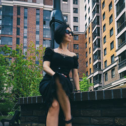 A pretty charming middle-aged woman in a black dress and sunglasses strolls through the city street