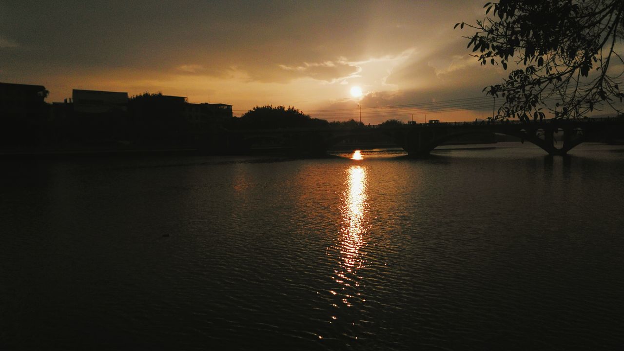 water, sunset, reflection, architecture, river, built structure, city, tranquil scene, waterfront, scenics, cloud, building exterior, calm, sky, tranquility, sun, cloud - sky, orange color, dark, nature, beauty in nature, outdoors, outline, no people, city life, skyline, bridge