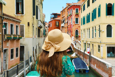 Rear view of woman walking by buildings in city