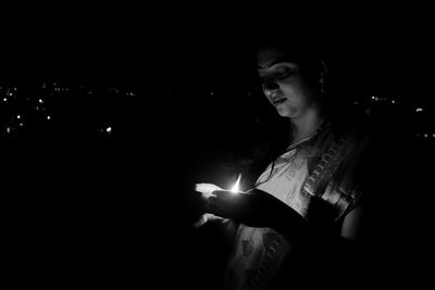 Young woman looking at illuminated lamp at night