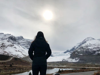 Rear view of woman standing on snowcapped mountain