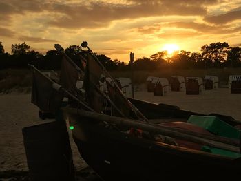 Boats moored on beach against sky during sunset