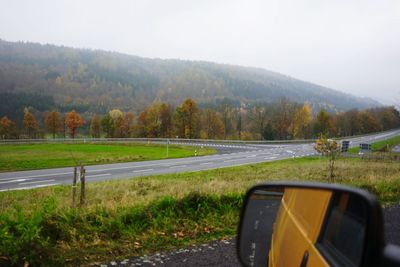 Car on road by field against sky