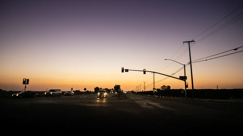 Cars on road against sky during sunset