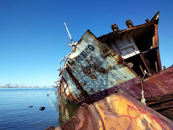 Abandoned boat moored in sea against sky