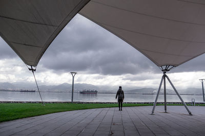 Rear view of man walking on umbrella against sky