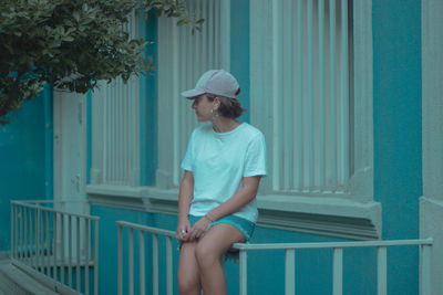 Man looking away while sitting on railing