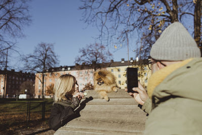 Woman holding cat by tree