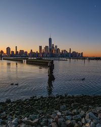 Sea and buildings against sky at sunset