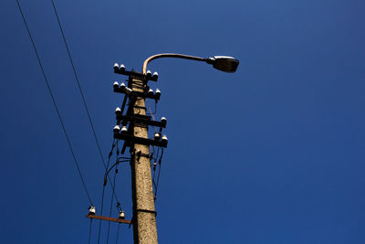 Low angle view of street light against blue sky