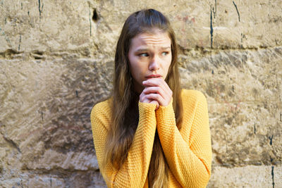Portrait of young woman standing against wall