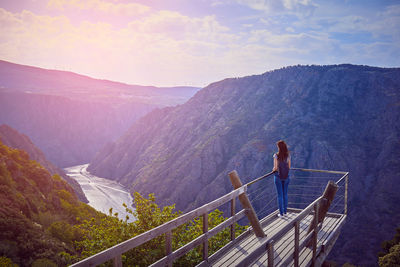 Rear view of woman looking at mountains while standing on observation point