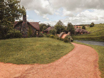 Scenic view of field by houses against sky