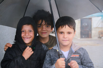 Little refugee children with umbrella in the rain, refugee with umbrella.