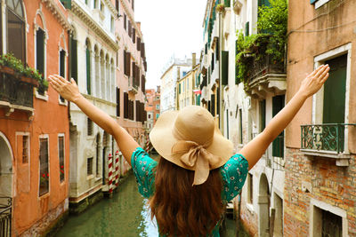 Rear view of woman walking by buildings in city