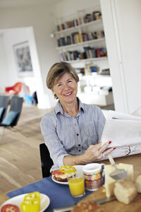 Portrait of mature woman eating breakfast at table