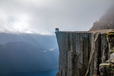 Low angle view of man standing on cliff against sky